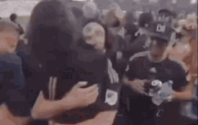 a woman is hugging a man in a crowd of people at a baseball game .