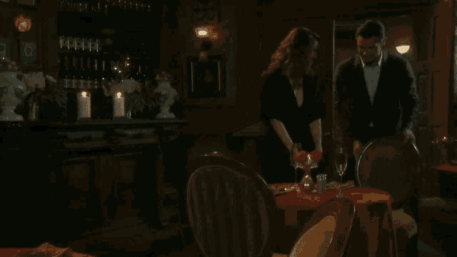 a man and a woman are standing at a table in a dark room