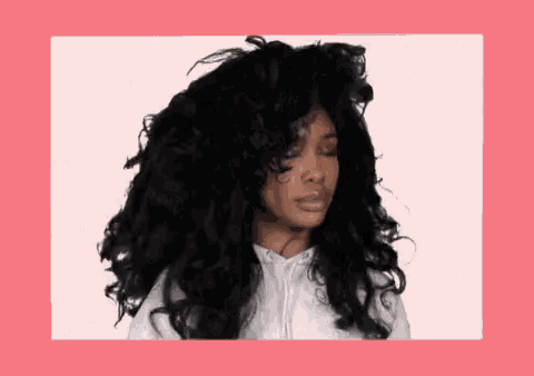a woman with very long black curly hair is wearing a white sweatshirt .