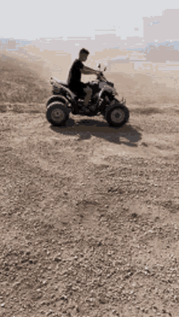 a man is riding a four wheeler in the dirt .