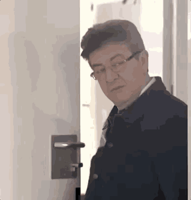 a man wearing glasses is standing in a doorway .