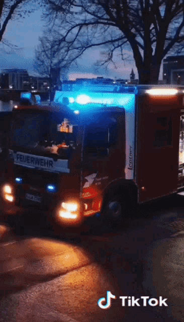 a red feuerwehr truck is driving down a street at night