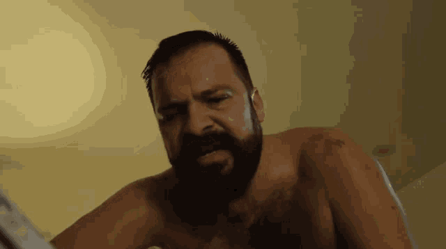 a shirtless man with a beard is looking at the camera