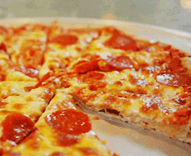 a pepperoni pizza with a slice taken out of it on a white plate