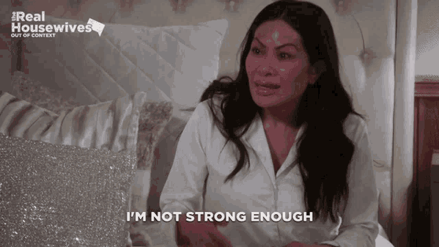 a woman sitting on a bed with the words i 'm not strong enough