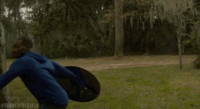 a man in a blue shirt is running with a shield in his hand