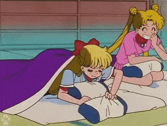 two girls are laying on a bed with a purple blanket .