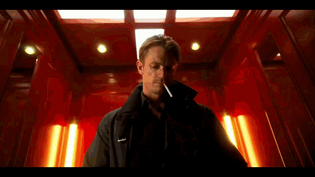 a man smoking a cigarette in an elevator with a red background