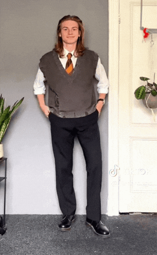 a man with long hair wearing a vest and tie