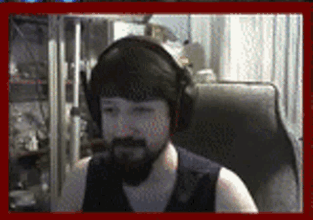 a man with a beard is wearing headphones and a black tank top .