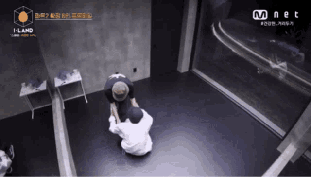 two people are kneeling in a room with a mnet logo on the bottom