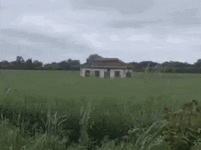 a small house is sitting in the middle of a field .