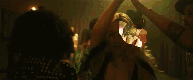 a group of people are dancing in a dark room with a woman in the foreground