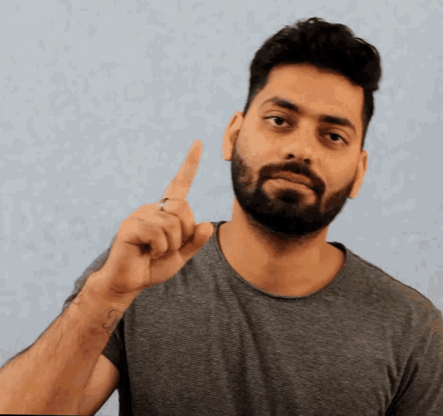 a man with a beard is pointing upwards
