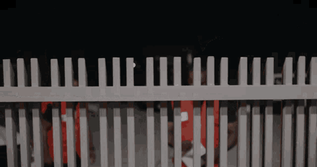 a white picket fence with a few people behind it in a dark room