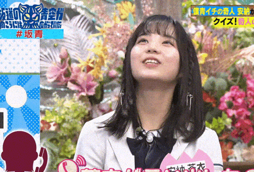 a woman stands in front of a display of flowers and a sign that says # 坂 青