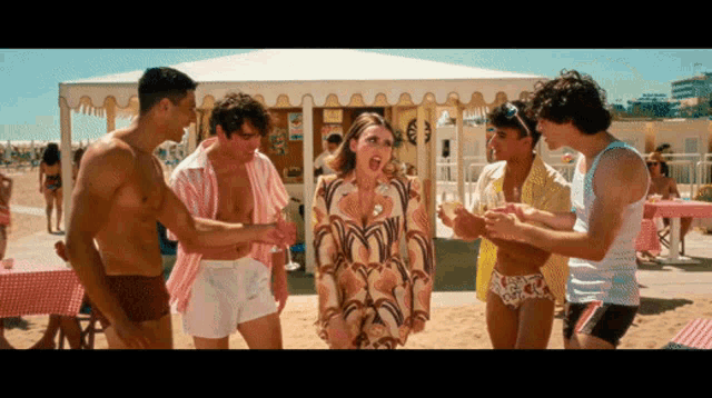 a group of people are standing on a beach with a woman screaming in the middle