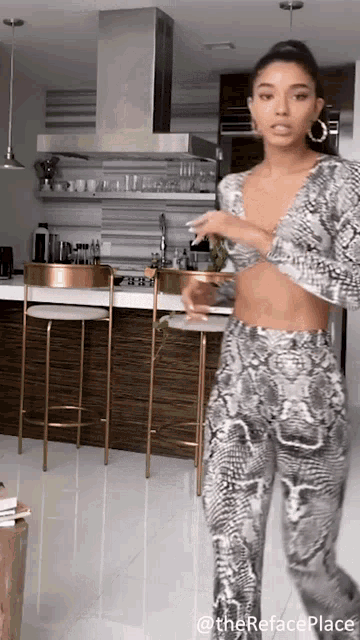 a woman in a snake print top and pants is standing in a kitchen