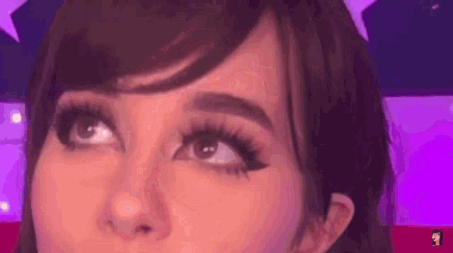 a close up of a woman 's face with long eyelashes looking up at the camera .