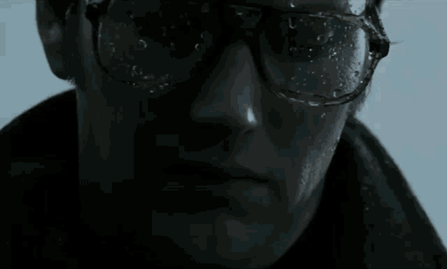 a close up of a man 's face with glasses and water dripping from them