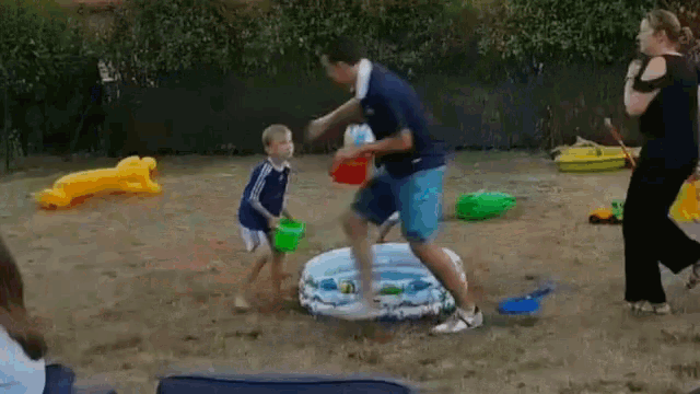 a group of people are playing in a sandy area with a pool and toys .