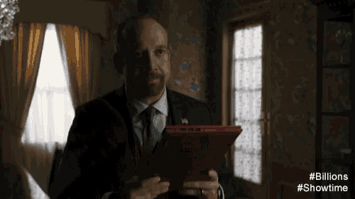 a man in a suit and tie is holding a red folder in his hands .