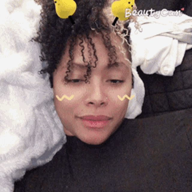 a woman wearing a bee headband is laying on a bed