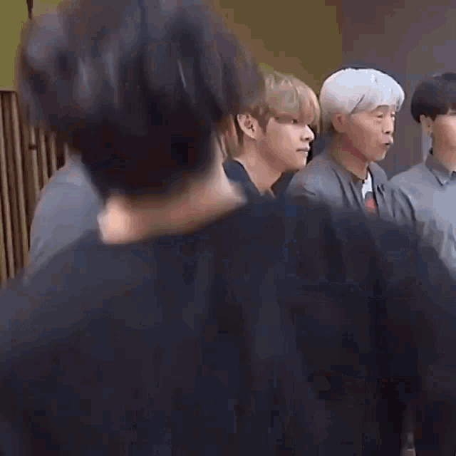 a group of young men are standing next to each other in a room with their hands in their pockets .