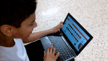 a young boy is typing on a laptop with a website open