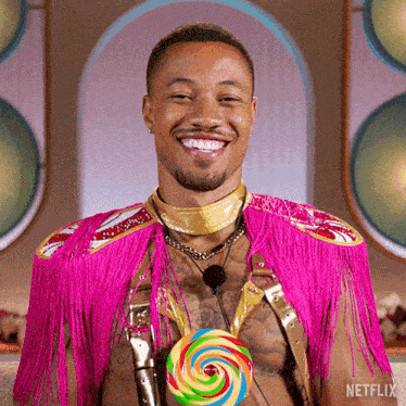 a man in a pink outfit is holding a colorful lollipop and smiling
