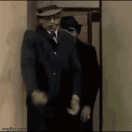 two men in suits and hats are standing in a doorway .