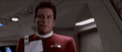 a man in a red jacket is standing in a room with the words `` fuck this shit '' written on the screen .