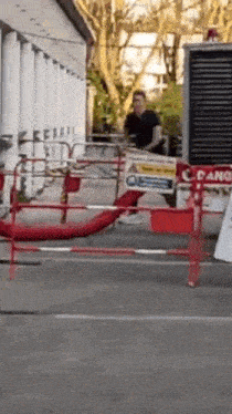 a man is standing behind a red barrier that says danger on it