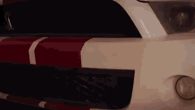 a close up of the front of a white mustang with red and white stripes on it .