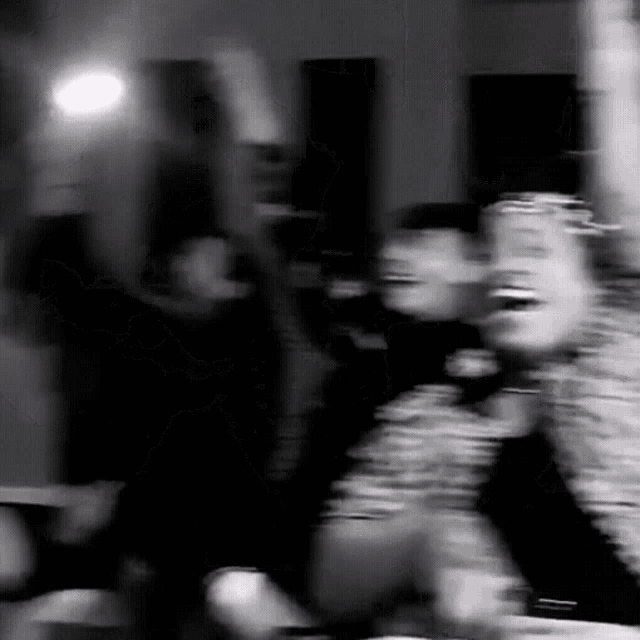 a blurry black and white photo of a group of people laughing and dancing .