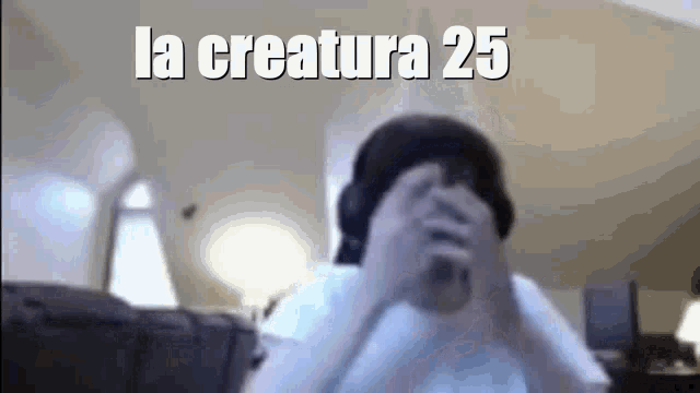 a person is covering their face with their hands and the words la creature 25 are above them .