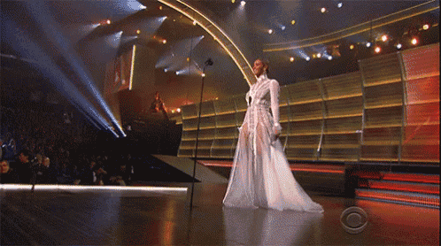a woman in a white dress is standing on a stage holding a microphone .
