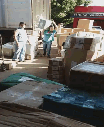 a man carrying a stack of boxes in front of a truck that says estetica