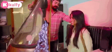 a man and a woman are standing next to each other in a room . the woman is looking at the man .