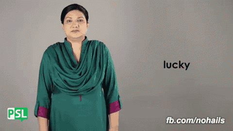 a woman in a green dress says the word lucky in sign language .