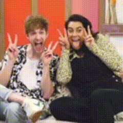 a man and a woman are sitting on the floor and giving peace signs