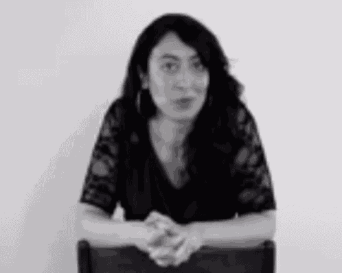 a woman is sitting in a chair with her hands folded in front of her .
