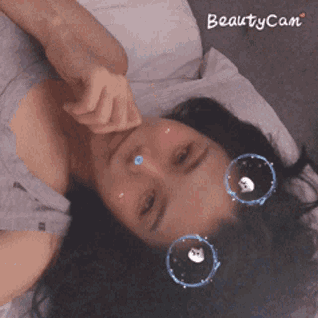 a woman is laying on a bed wearing a beautycam filter