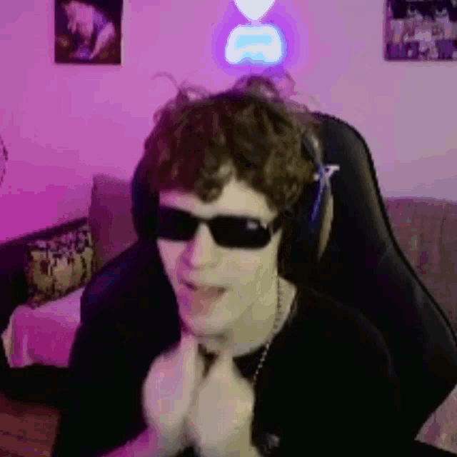 a man wearing sunglasses and headphones is sitting in a chair in a room .