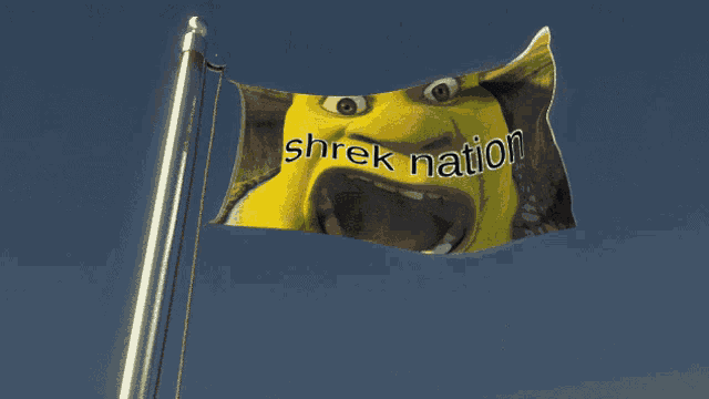 a shrek nation flag flies in the wind against a blue sky