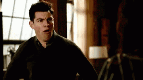 a man is making a funny face in front of a window in a living room .