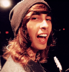 a young man with long hair wearing a beanie and a gray sweater