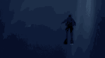 a man is standing in the mouth of a large shark in the dark .