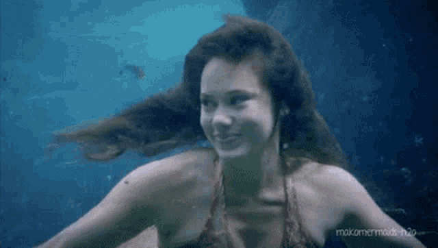a woman in a bikini is swimming underwater in a pool .