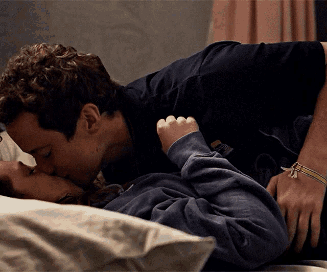 a man in a black shirt kisses a woman in a gray sweatshirt